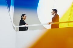 Man and woman talking. Japan. Primary color: yellow.