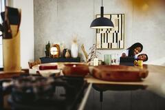 Smiling woman with kid on her lap sitting at a the kitchen table with tablet.