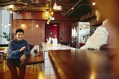 Man talking to waitress while sitting in restaurant.