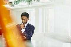 Man in suit looking at his phone. India. Primary color: yellow.