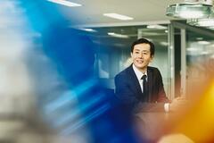 Man and woman talking in an office. Japan. Primary color: blue.