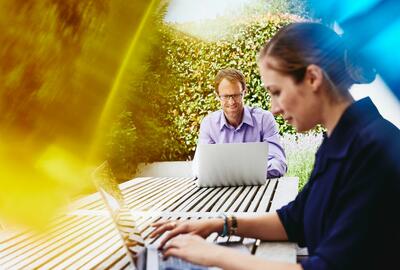 a man and a woman are using their laptops