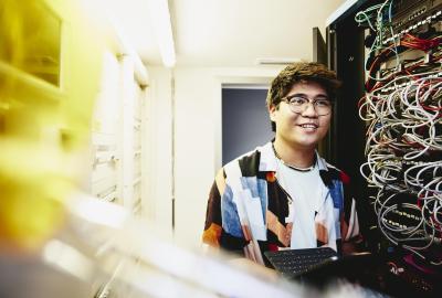 Smiling man holding an tablet standing in a servers room.