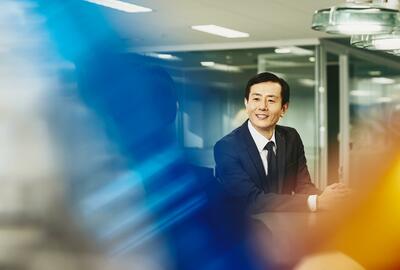 Man and woman talking in an office. Japan. Primary color: blue.