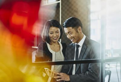 Man and woman looking at chell phone. China. Primary colors: red and yellow.