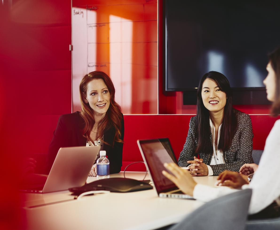 Group of business women having a meeting. Primary color: red.