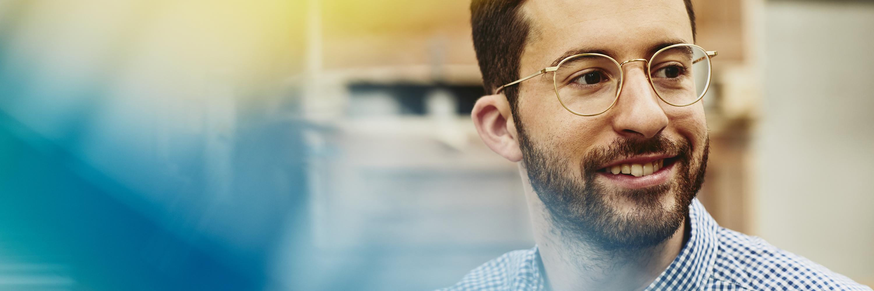 Male caucasian worker in logistics environment. Wearing glasses. Checkered shirt. Groomed beard and moustache. Primary color blue. Secondary color yellow.