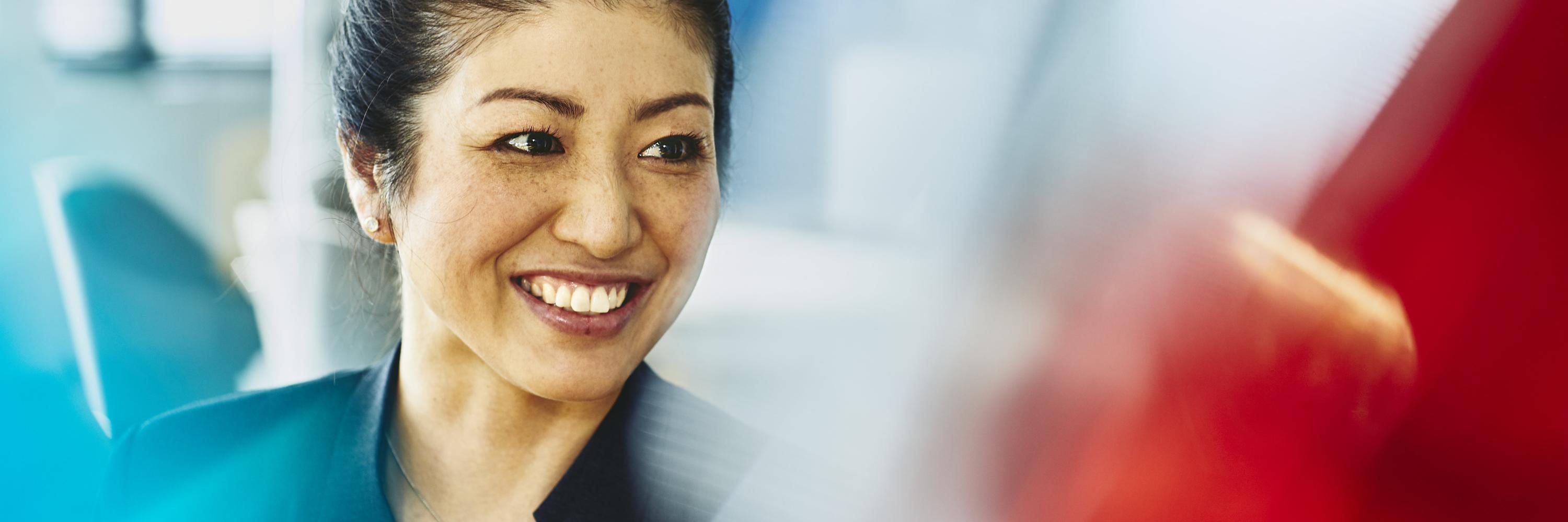 Woman in suit smiling. Japan. Primary color: red.