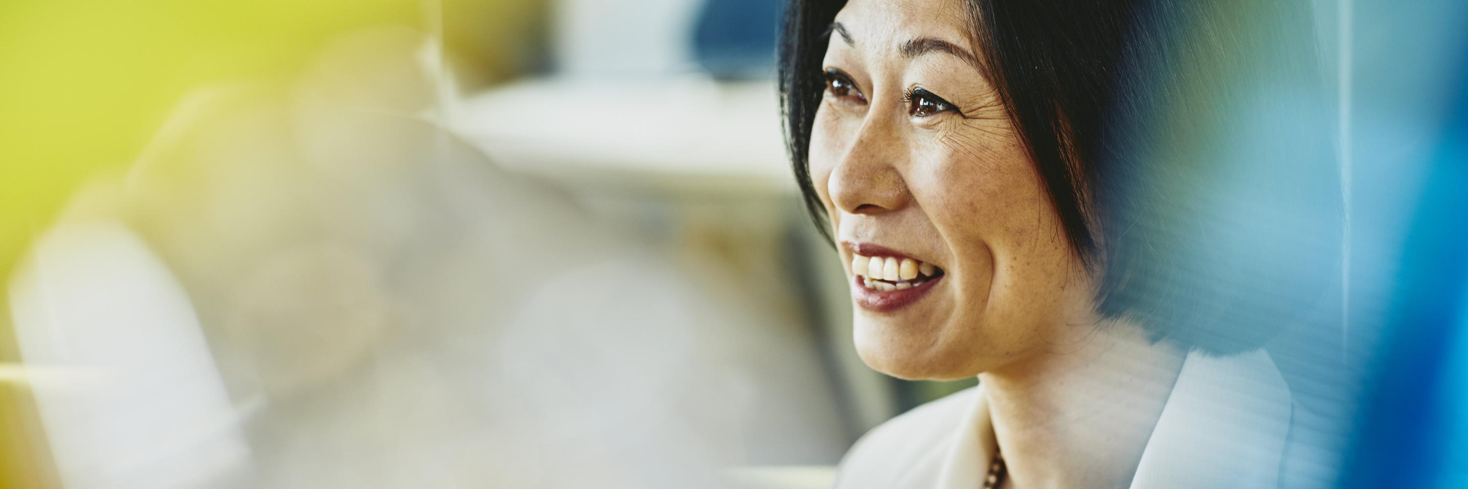 Older woman smiling. Japan. Primary color: yellow.