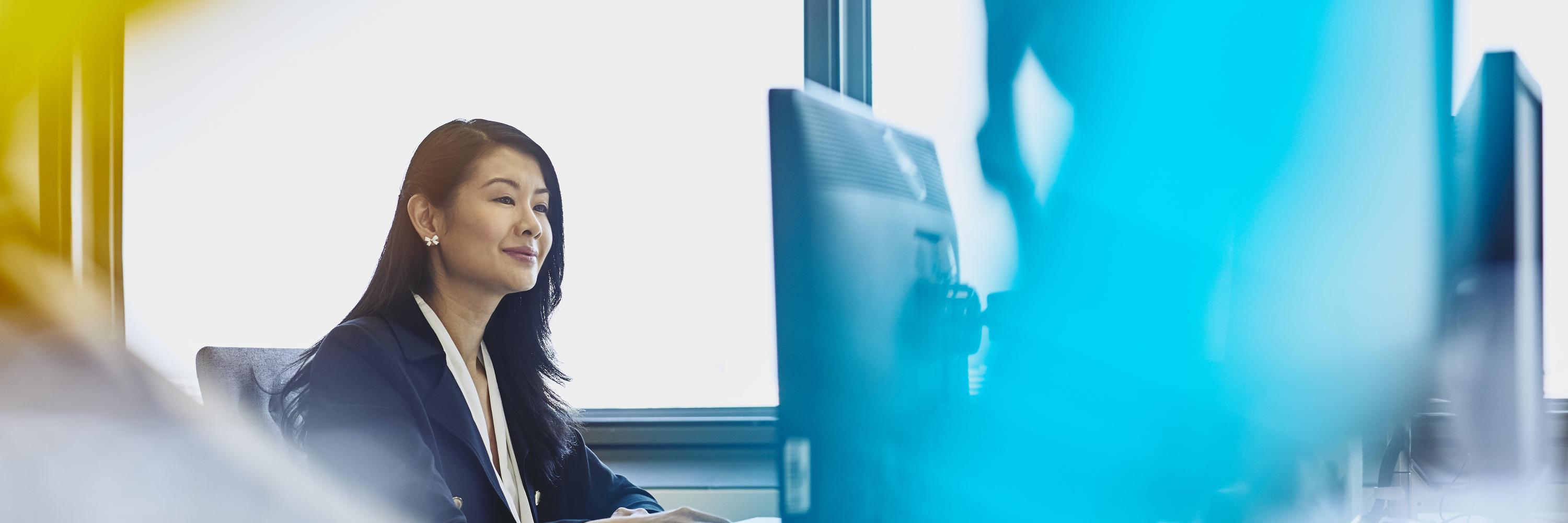 Woman working on her desktop computer. China. Primary color: blue.